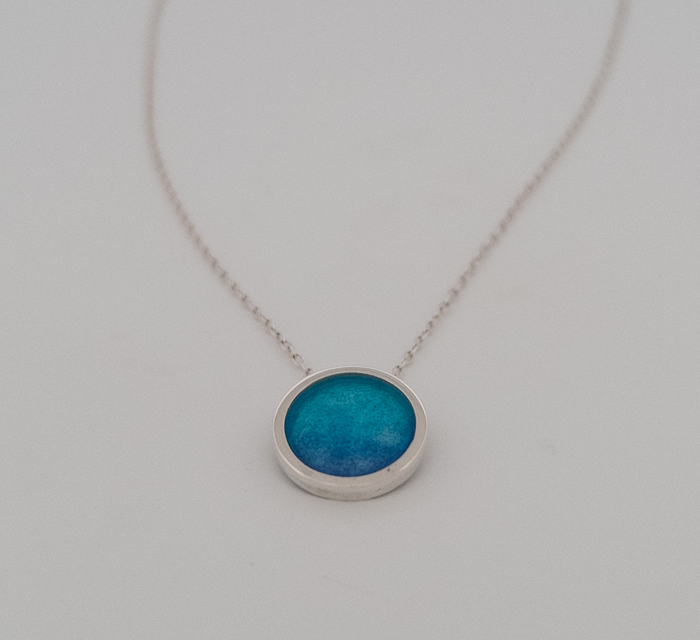 Circular textured necklace with peacock blue enamel.